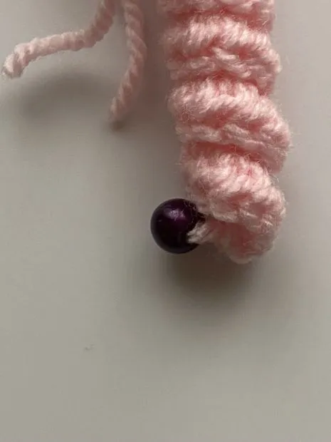 gehäkeltes rosa Glückswürmchen mit violetter Mütze
